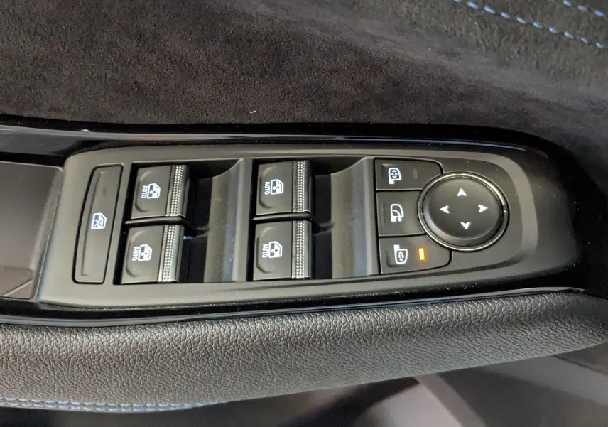Gros plan sur les commandes des vitres électriques et réglages des rétroviseurs dans l'habitacle noir du Renault Austral gris schiste.