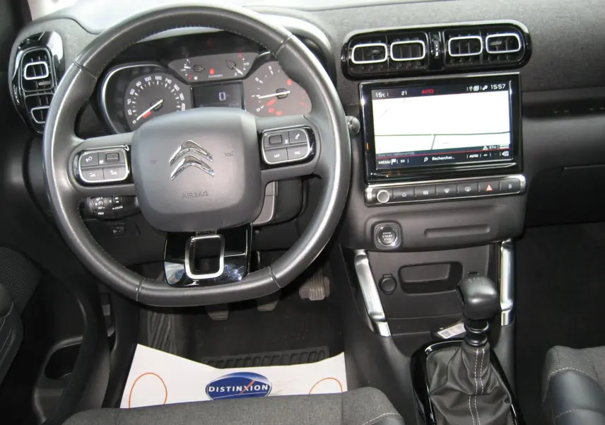 Vue intérieure avant centrée sur le volant noir et la console avec écran tactile du Citroën C3 Aircross gris platinium 2022.
