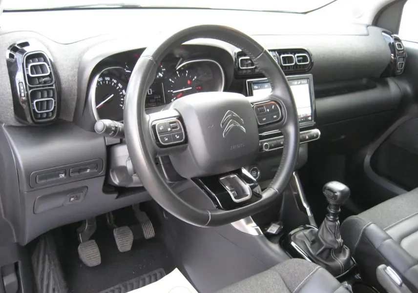 Intérieur du Citroën C3 Aircross gris platinium, vue côté conducteur sur volant, tableau de bord et levier de vitesse manuel.