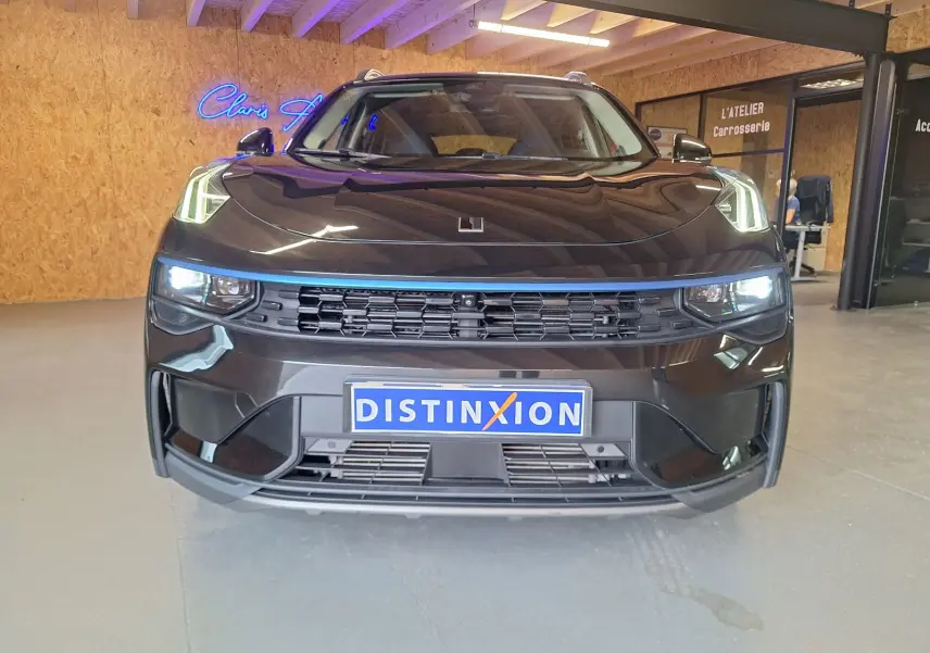 Vue frontale d'un SUV LYNK & CO 01 noir avec phares allumés et calandre noire dans un garage.