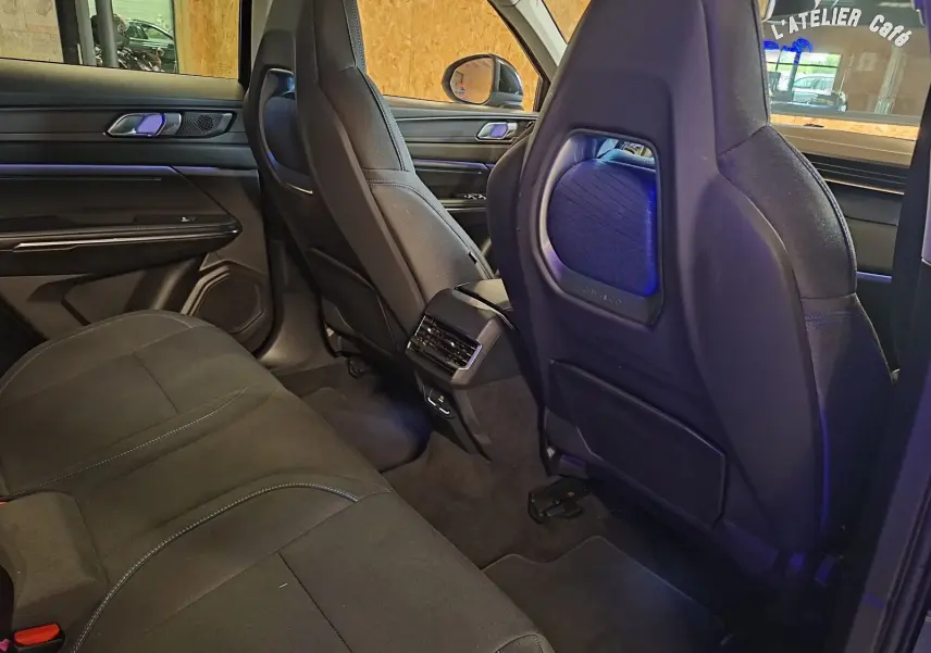 Vue intérieure arrière côté droit du LYNK & CO 01 noir, sièges en tissu noir avec surpiqûres bleues et éclairage d'ambiance bleu.