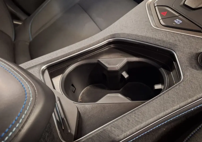 Gros plan sur le porte-gobelets central noir et la console avec surpiqûres bleues à l'intérieur du Lynk & Co 01 hybride 2023.
