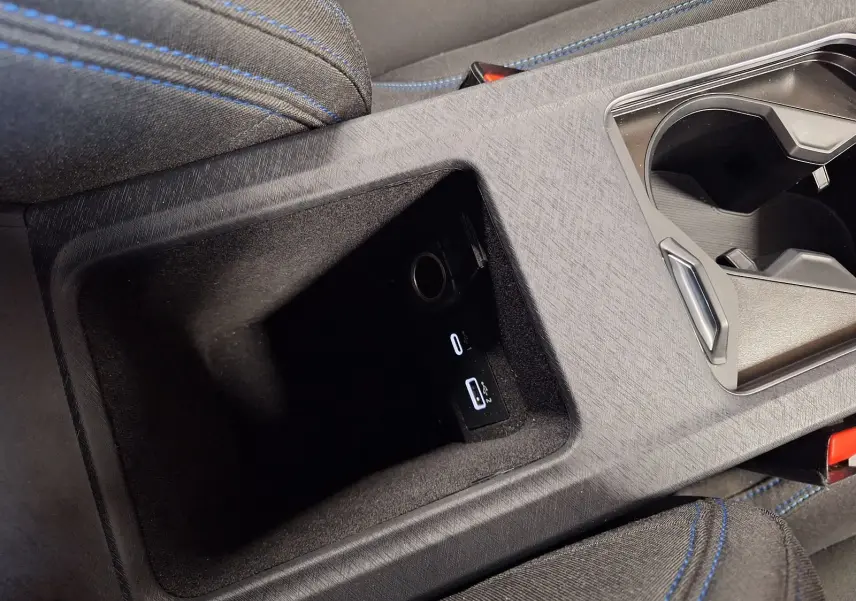 Gros plan sur la console centrale noire du Lynk & Co 01 avec prises USB et tissu noir aux surpiqûres bleues.