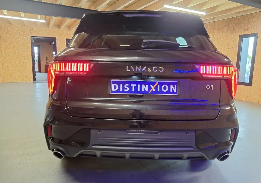 Vue arrière d'un SUV LYNK & CO 01 noir avec feux LED allumés dans un garage lumineux.