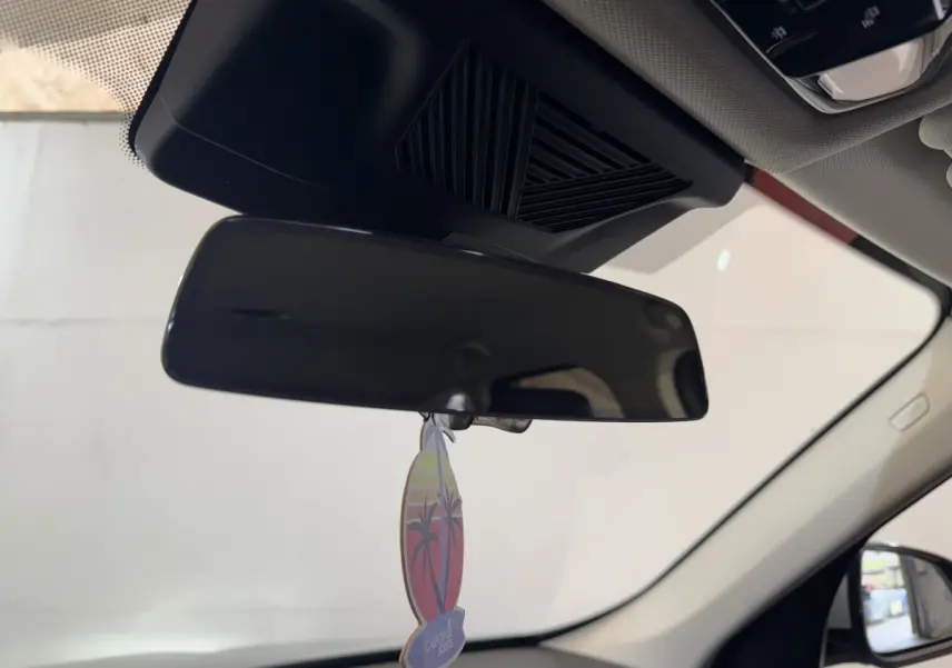 Vue intérieure centrée sur le rétroviseur intérieur noir avec un parfum suspendu dans un BMW X1 gris foncé 2024.