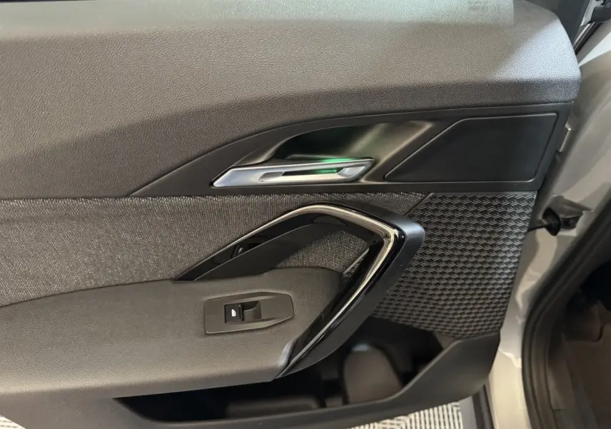 Vue rapprochée de la porte avant droite du BMW X1 2024 gris foncé, avec poignée chromée et habillage texturé.