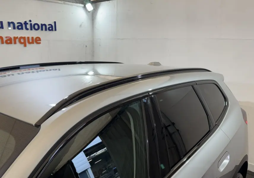 Vue rapprochée du toit et des vitres teintées côté droit du BMW X1 gris foncé en intérieur.