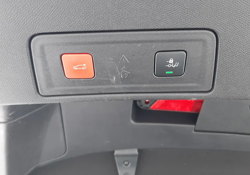 Gros plan sur les boutons de commande du coffre et de la fermeture automatique dans le coffre d'une Peugeot 508 blanche.