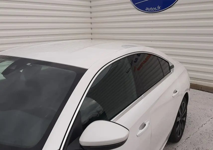Vue 3/4 arrière droite d'une Peugeot 508 blanche avec vitres teintées, jantes noires et rétroviseur assorti.