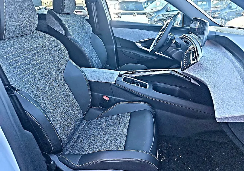 Vue intérieure côté conducteur du Peugeot 5008 Hybrid 145 allure e-dcs6 2025 avec sièges tissu et cuir noir et gris.