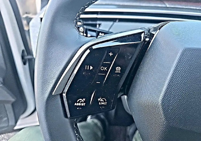 Gros plan sur les commandes multifonctions du volant cuir noir du Peugeot 5008 Hybrid 145 allure e-dcs6 blanc.