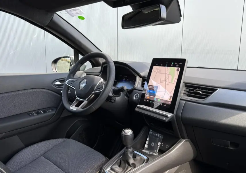 Vue intérieure côté conducteur du Renault Captur 2025 avec tableau de bord noir et écran tactile vertical affichant la navigation.