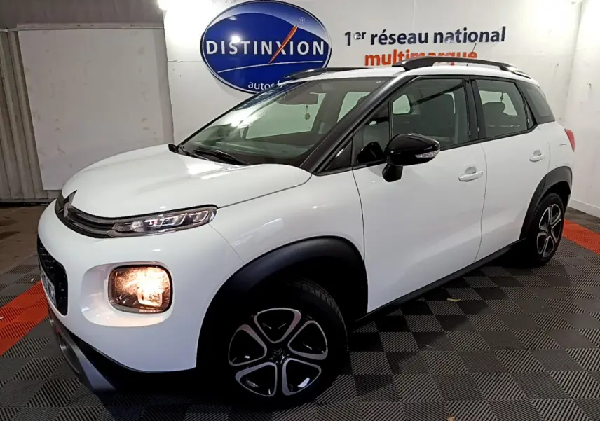 Citroën C3 Aircross blanc vue 3/4 avant droit, feux avant allumés et jantes noires distinctives.
