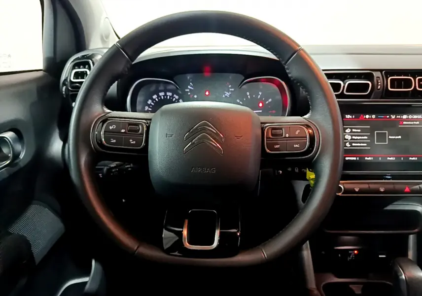 Vue centrée sur le volant cuir noir du Citroën C3 Aircross, avec tableau de bord et écran tactile visibles.