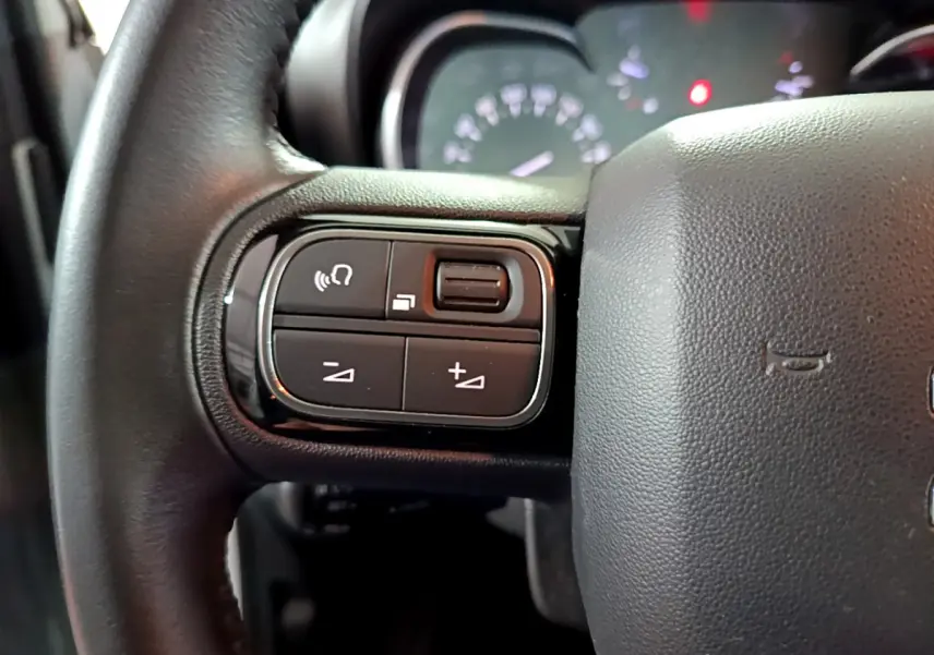 Gros plan sur les commandes gauche du volant cuir d’une Citroën C3 Aircross 2019, avec tableau de bord en arrière-plan.