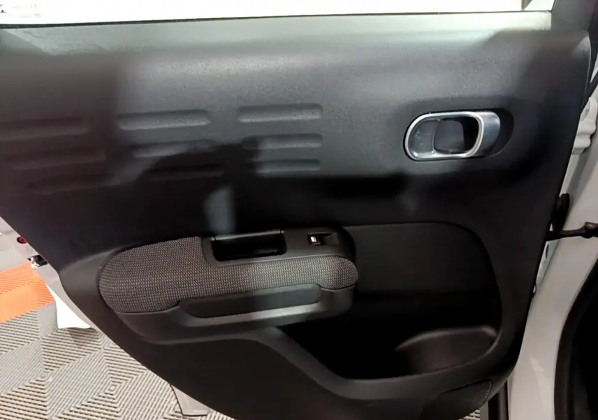 Vue rapprochée de la porte arrière droite noire du Citroën C3 Aircross blanc, avec poignée intérieure argentée.