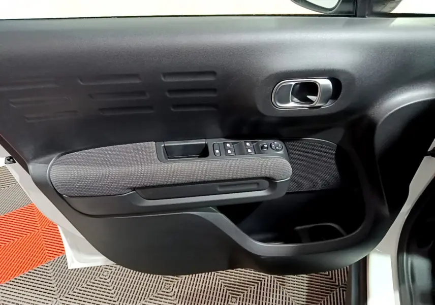 Gros plan sur la porte avant gauche noire et grise du Citroën C3 Aircross blanc, avec commandes électriques des vitres.