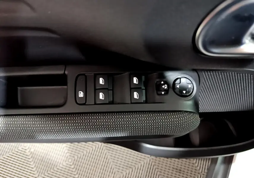 Gros plan sur la commande des vitres et rétroviseurs côté gauche intérieur d'une Citroën C3 Aircross blanche.