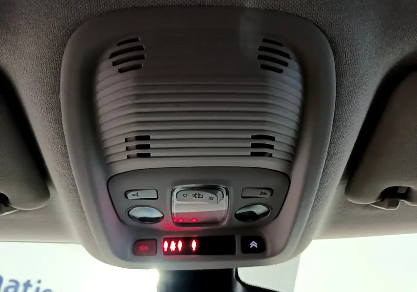 Vue en contre-plongée du plafonnier gris avec commandes lumineuses et bouton SOS du Citroën C3 Aircross blanc.