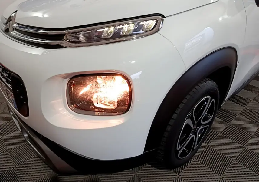 Gros plan sur l'avant droit blanc du Citroën C3 Aircross 2019 avec phare antibrouillard allumé et jante noire.