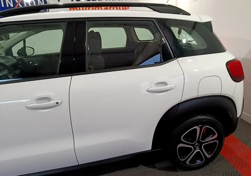 Vue latérale droite d'une Citroën C3 Aircross blanche, avec toit noir et jantes distinctives en alliage.