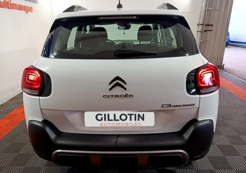 Vue arrière d'un Citroën C3 Aircross blanc avec feux arrière allumés dans un garage.