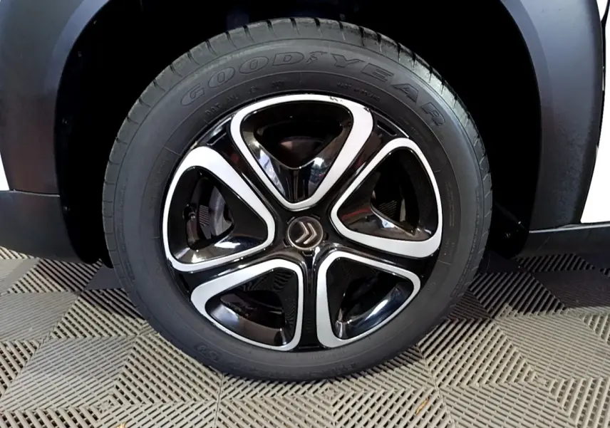 Gros plan sur la roue avant droite du Citroën C3 Aircross blanc avec jante noire et argentée au design distinctif.