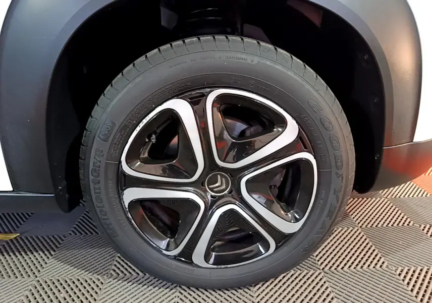 Gros plan sur la roue avant droite du Citroën C3 Aircross blanc, mettant en valeur la jante noire et argentée distinctive.
