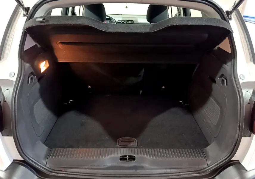 Coffre ouvert vu de l'arrière d'une Citroën C3 Aircross blanche, espace de chargement noir avec tablette relevée.