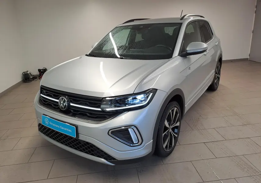 Volkswagen T-Cross 2025 Reflet d'argent en 3/4 avant droit avec phares LED allumés et jantes R-Line noires.
