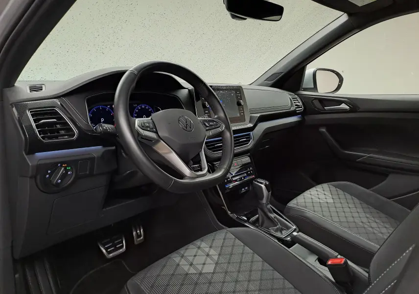Vue intérieure côté conducteur du Volkswagen T-Cross 2025 R-Line Edition avec volant multifonction et sièges tissu à motif.