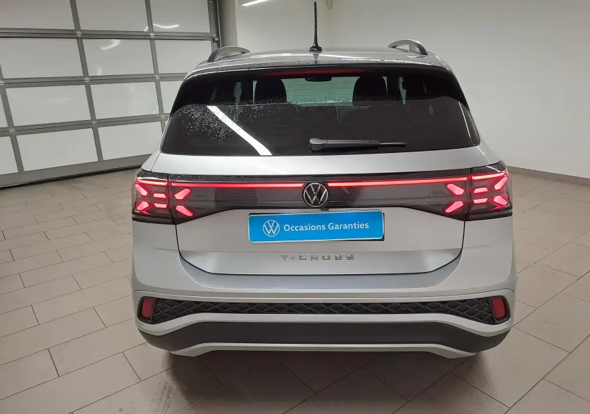 Vue arrière d'un Volkswagen T-Cross 2025 argent avec feux LED allumés et logo VW au centre du hayon.