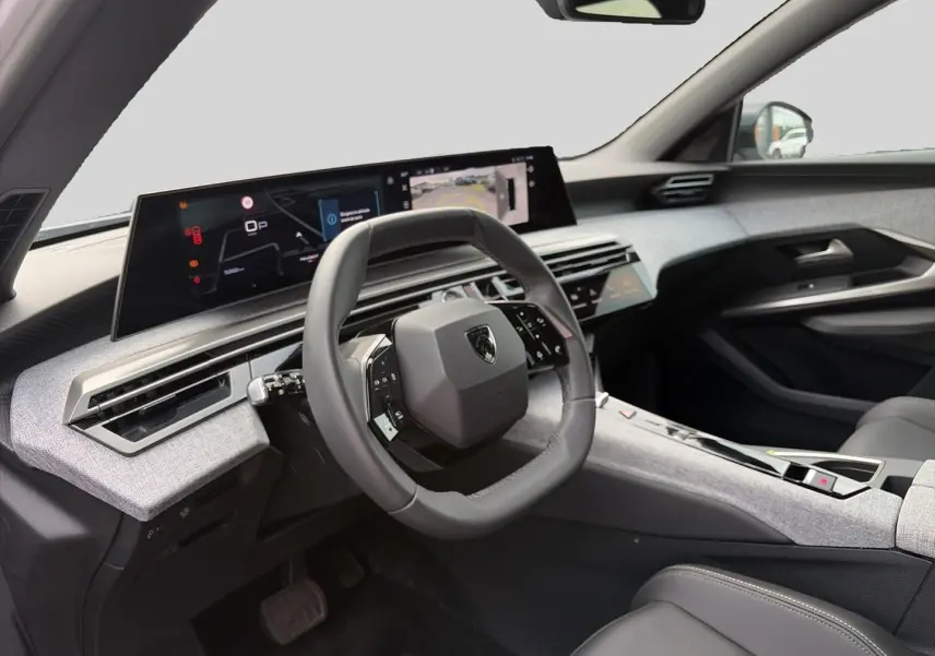 Intérieur Peugeot 5008 Hybrid 2025 vu côté conducteur, volant cuir, tableau de bord numérique et habillage gris clair.