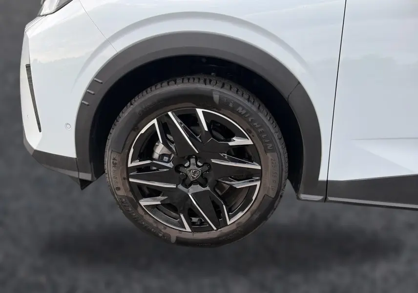 Gros plan sur la roue avant droite et l'aile blanche d'un Peugeot 5008 Hybrid 145 allure e-dcs6 2025.