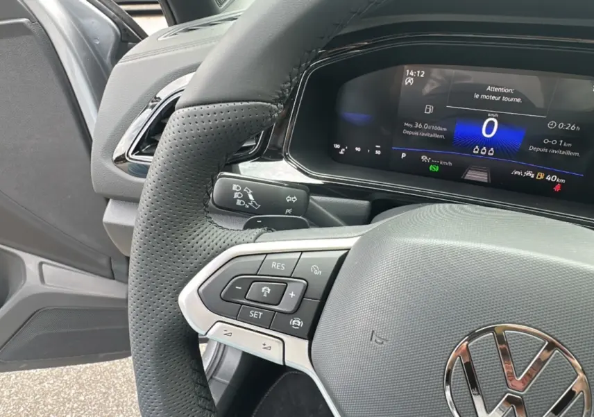 Gros plan sur le volant perforé et le tableau de bord numérique du Volkswagen T-Roc R-Line Black gris pyrite 2025.