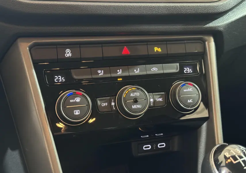 Vue rapprochée du tableau de bord du Volkswagen T-Roc gris foncé, montrant la climatisation digitale et la boîte manuelle.