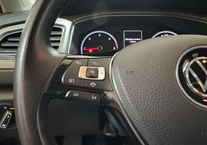 Gros plan sur le volant cuir côté gauche du Volkswagen T-Roc 2021 avec commandes multifonctions et tableau de bord partiellement visible.