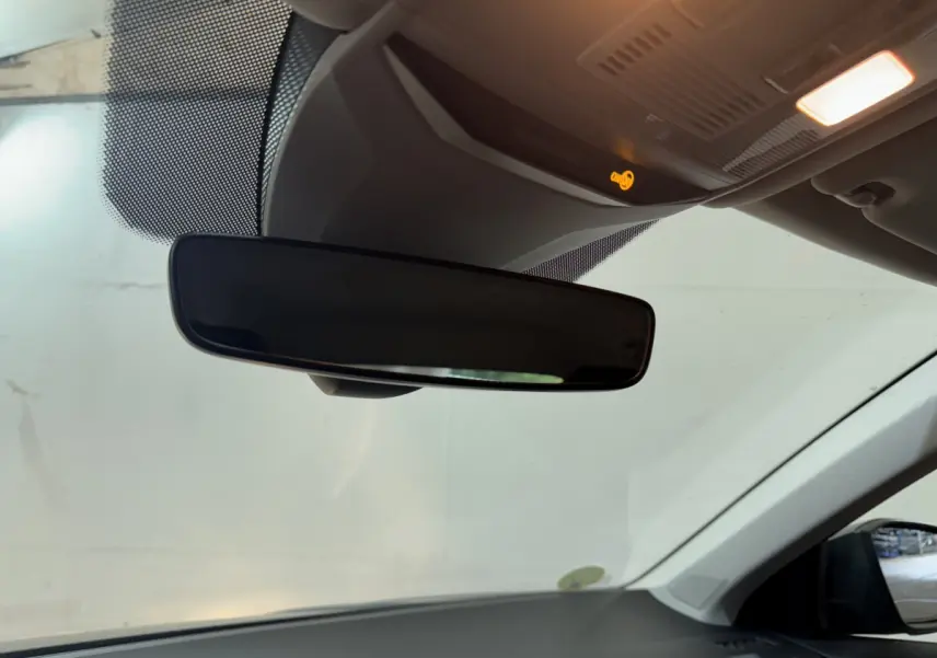 Vue intérieure centrée sur le rétroviseur intérieur d'un Volkswagen T-Roc gris foncé, avec plafonnier allumé.