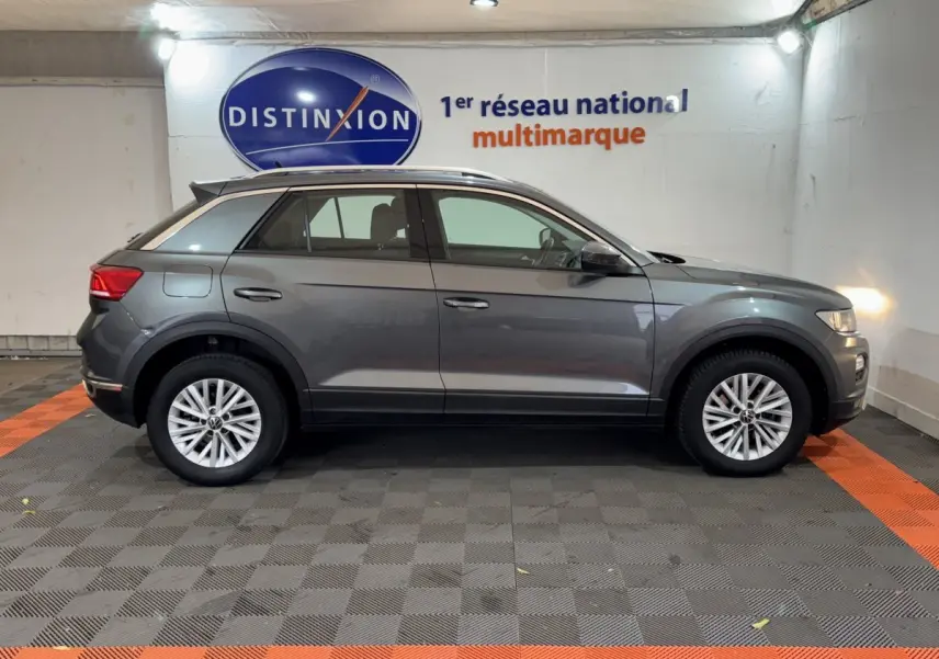 Profil droit d'un Volkswagen T-Roc gris foncé 2021 garé en intérieur avec jantes alliage et rails de toit noirs.