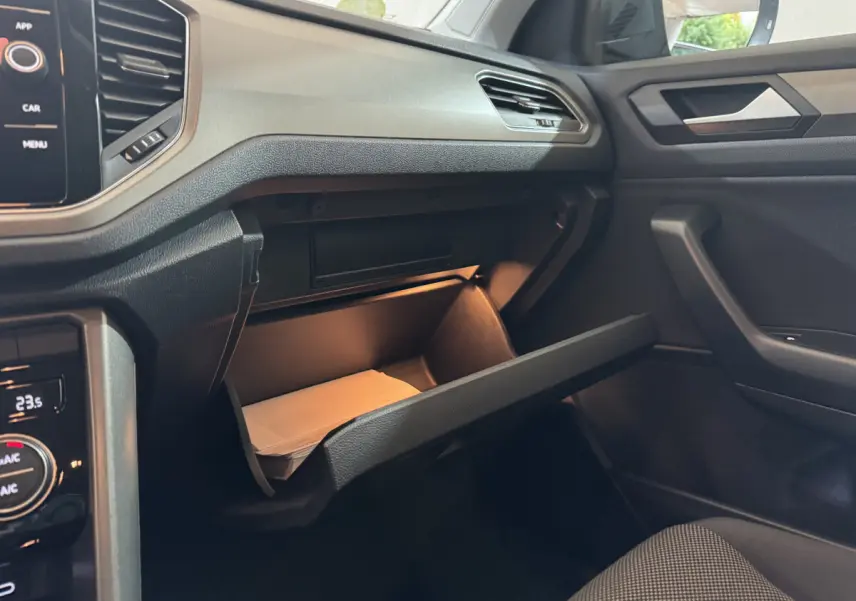 Intérieur du Volkswagen T-Roc 1.6 TDI 2021, vue côté passager sur boîte à gants ouverte et tableau de bord noir.