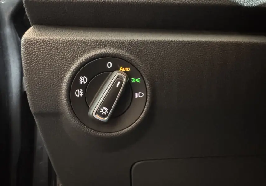 Gros plan sur le bouton de commande des phares du Volkswagen T-Roc 1.6 TDI 115 Lounge Business, intérieur noir.