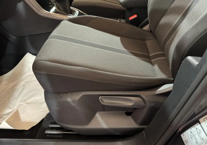 Gros plan sur le siège avant gauche gris foncé du Volkswagen T-Roc 2021, montrant la commande de réglage manuel.