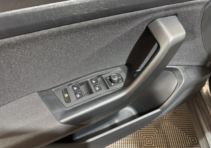 Vue rapprochée de la porte avant gauche du Volkswagen T-Roc gris foncé, montrant les commandes des vitres et rétroviseurs.