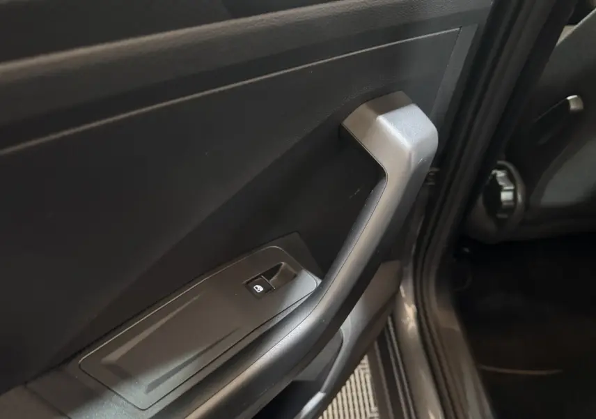 Gros plan sur la poignée intérieure et commande de vitre côté conducteur du Volkswagen T-Roc gris foncé 2021.
