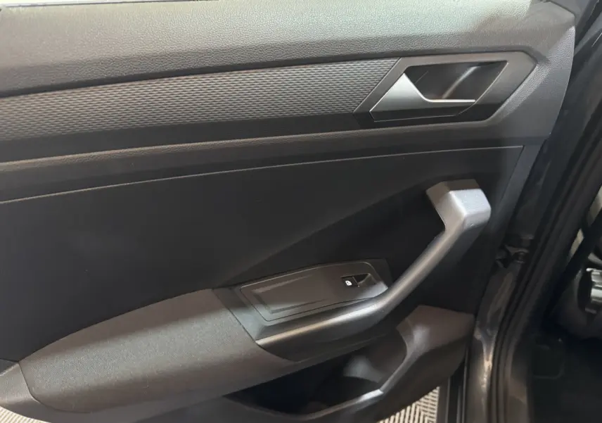 Vue rapprochée de la porte avant droite gris foncé du Volkswagen T-Roc 1.6 TDI 115 Lounge Business avec poignée et bouton de verrouillage.