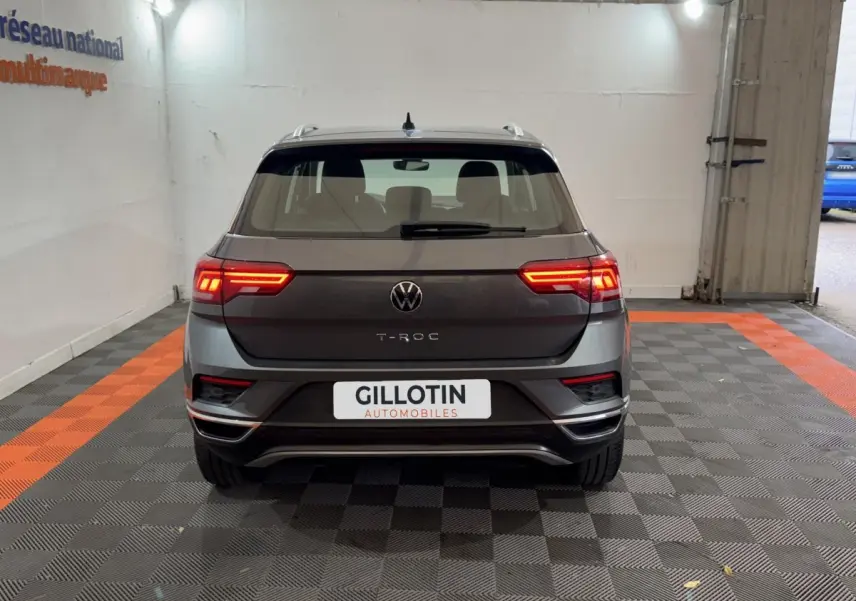 Vue arrière d’un Volkswagen T-Roc gris foncé avec feux LED allumés dans un garage intérieur.