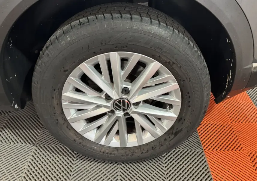 Gros plan sur la roue avant droite d’un Volkswagen T-Roc gris foncé avec jante alliage à multiples branches.