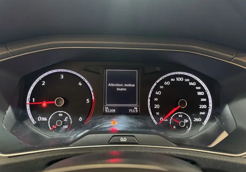 Vue rapprochée du tableau de bord du Volkswagen T-Roc gris foncé, affichant les compteurs et un message d'alerte moteur.