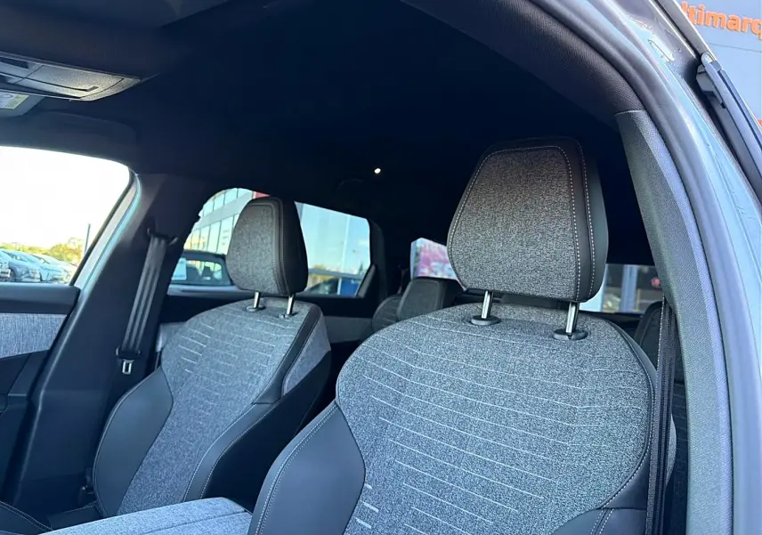 Vue intérieure côté gauche montrant les sièges avant gris tissu et cuir du Peugeot 5008 Hybrid 145 allure e-dcs6 2025.