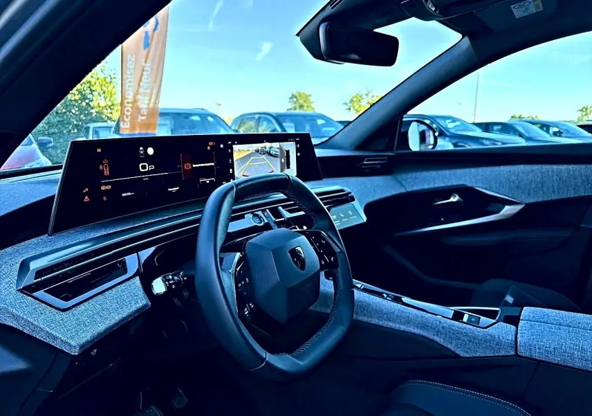 Vue intérieure côté conducteur du Peugeot 5008 Hybrid 145 allure e-dcs6 2025 avec tableau de bord numérique et tissus gris.